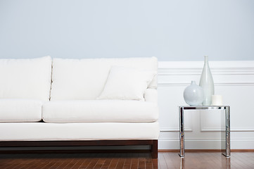 Image showing White Sofa and Glass End Table Against Blue Wall