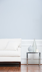 Image showing White Sofa and Glass End Table Against Blue Wall