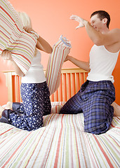 Image showing Young Couple Kneeling on Bed Having a Pillow Fight