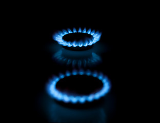 Image showing Two gas burners with flames on dark background