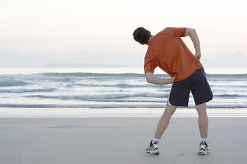 Image showing Jogger doing stretching on a beach