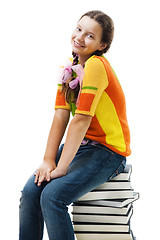 Image showing Happy teenager sit on stack of books