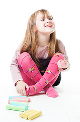 Image showing Little girl with chalks stick her tongue out