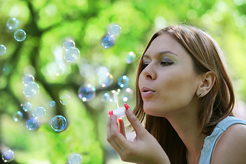 Image showing young woman blows soap bubbles