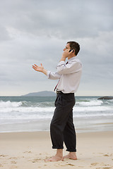Image showing Businessman talking on cell phone on a beach