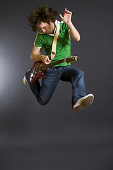 Image showing passionate guitarist jumps in the air