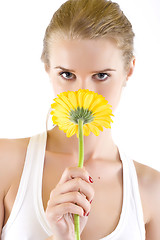 Image showing young woman smelling a yellow flower