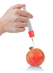 Image showing hand holds the syringe on pomegranate