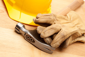 Image showing Yellow Hard Hat, Gloves and Hammer on Wood