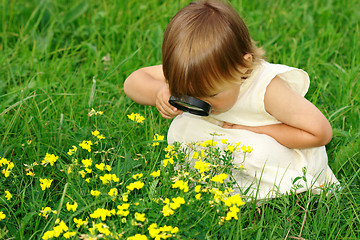 Image showing Child looking at flowers through magnifying glass
