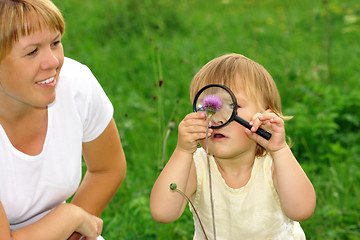 Image showing Child looking at flower through magnifying glass
