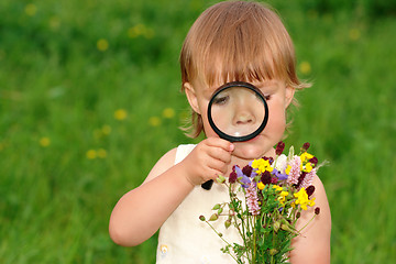 Image showing Child looking at flowers through magnifying glass