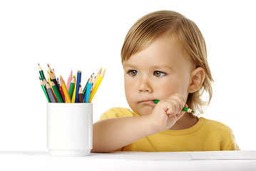 Image showing Child bites green crayon and thinks about ideas