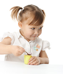 Image showing Little girl eats yogurt