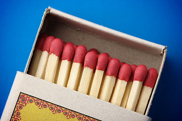 Image showing Red matchsticks in the box on blue background