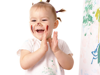 Image showing Little girl play with paints, clapping her hands