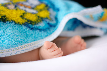 Image showing Adorable toddler's feet on white bedsheet