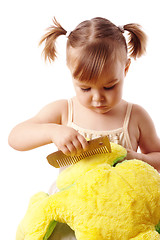 Image showing Cute girl combing her soft toy