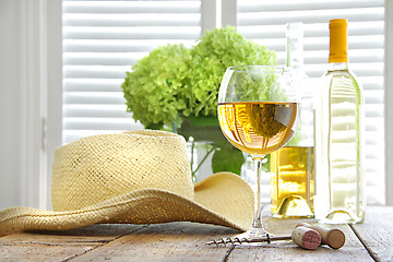 Image showing Glass of wine with straw hat on table