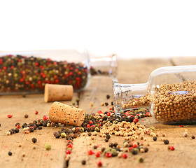 Image showing Peppercorns in glass bottles on wood table