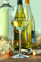 Image showing Glass of white wine with bottles