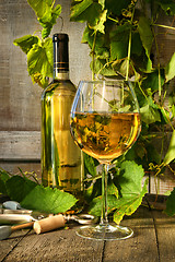 Image showing Glass of white wine and bottle on barrel 