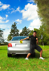 Image showing Excited male holding licence permit plates beside silver car