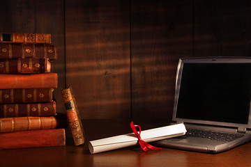 Image showing Antique books, diploma with laptop on desk