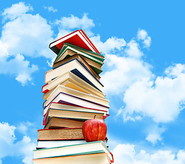 Image showing Pile of books and apple against blue sky