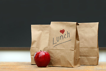 Image showing Lunch bags with  apple on school desk