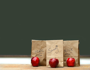 Image showing Lunch bags on desk with red apples