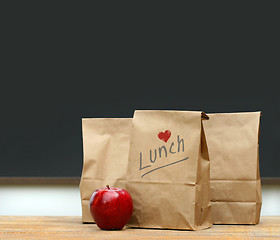 Image showing Lunch bags with  apple on school desk