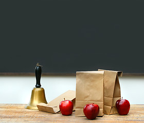 Image showing Lunch bags with apples and school bell on desk