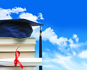 Image showing Stack of books with diploma against blue sky