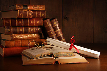 Image showing Pile of old books with glasses on desk