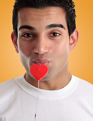 Image showing Amorous man kissing love heart on a stick