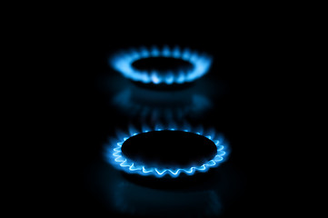 Image showing Two gas burners with flames on dark background