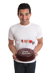 Image showing Man carrying chocolate cake decorated with hearts