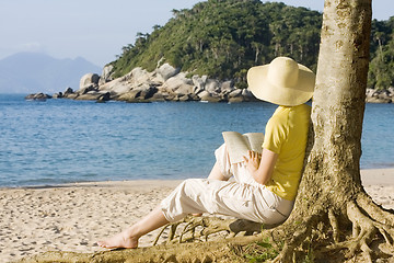 Image showing Woman reading a book on a beach