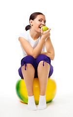 Image showing Young woman sit on ball with apple