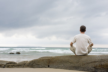 Image showing Man meditating on a rock at the sea