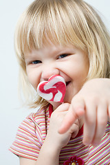 Image showing Cute little girl with a heart shape lollipop