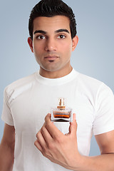 Image showing A man holds a bottle of cologne