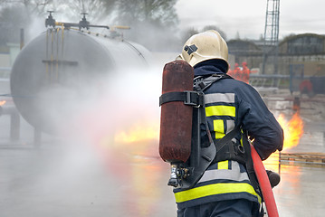 Image showing Firefighter extinguishing tank fire