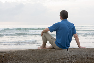 Image showing Man sitting on a rock at the sea