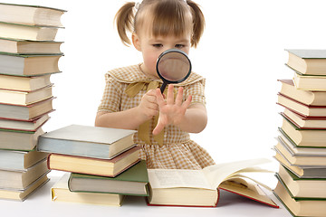Image showing Little girl looking at the book through magnifier, back to school