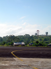 Image showing airport tarmac runway with houses in jungle