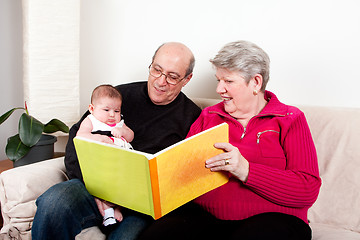 Image showing Grandparents reading book to baby girl.