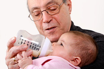 Image showing Grandpa bottle feeding baby girl