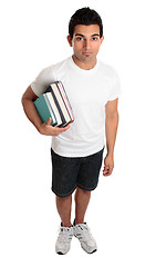 Image showing Male college student standing with textbooks under one arm